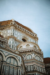 Fototapeta premium Magnificent architectural details of Florence Cathedral against a clear sky. Intricate marble patterns and historical textures of iconic Duomo, a symbol of Italian Renaissance artistry and grandeur.