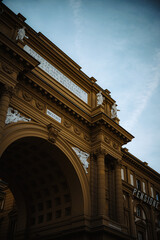 Obraz premium Intricate architectural details adorn a historic building in Florence, Italy, featuring ornate archways, classical statues, and columns under a vast sky, evoking European charm and travel.
