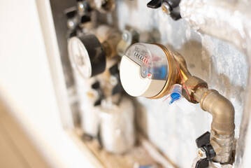 Close-up photo of water meter connected to pipe in utility box. Concept of consumption monitoring, household infrastructure, energy efficiency, billing, sustainability and economy.
