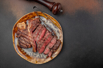 Juicy grilled T-bone steak cut into slices medium rare on a ceramic plate, perfect for delivery service promotion, advertising banners, restaurant menu design, or online food ordering platforms