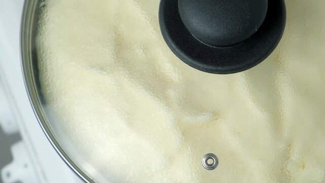 Frying omelet whipped mass in frying pan under lid cooking on kitchen gas stove. Recipe cuisine culinary ingredient. Preparing chicken eggs food dish. Super fluffy souffle egg omelet close-up.