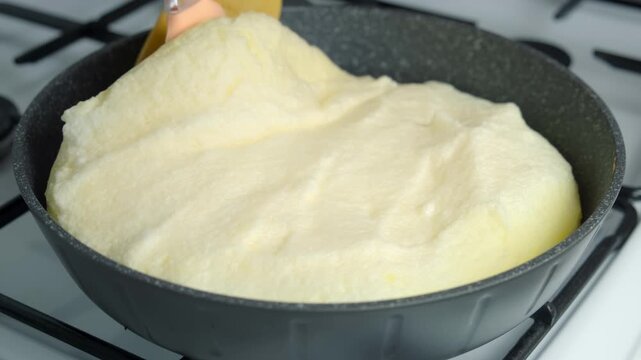 Frying omelet opening lid of frying pan turning it with spatula cooking on kitchen gas stove. Recipe cuisine culinary ingredient. Preparing chicken eggs food dish. Super fluffy egg omelet close-up.