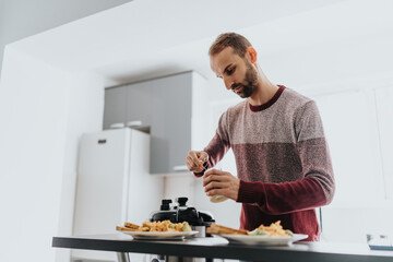 A man in a sweater is preparing a meal in a contemporary kitchen setting.