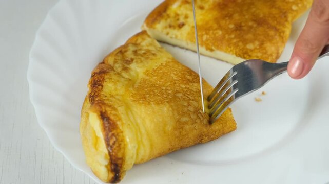 Woman cutting fried omelet on plate to eat cooking on kitchen at home. Recipe cuisine culinary ingredient. Preparing chicken eggs food dish. Super fluffy egg omelet, hands close-up.