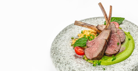 Juicy roasted rack of lamb chops served on a stylish plate with green pea puree, cherry tomatoes, basil leaves and golden garnish. gourmet food concepts. copy space