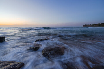 Wave water flowing between rocks on the shore.