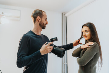 A photographer guiding a model during an indoor photo shoot in a studio setting. The interaction emphasizes direction and collaboration, with professional equipment and soft studio lighting.