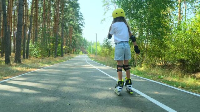 Girl is roller skating by forest, enjoying an active hobby in the open air.