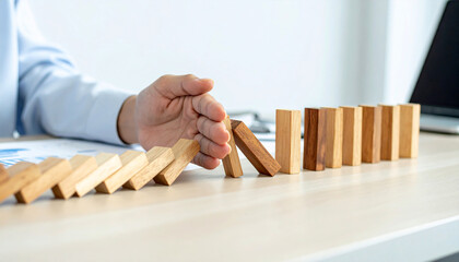A hand stopping a falling domino effect, symbolizing risk management