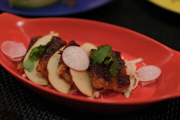 Meat with apples, radishes and cilantro leaves on a red plate. High quality photo
