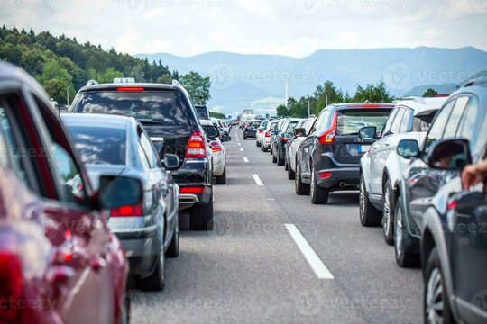 Heavy rush hour traffic congestion causing a long delay for commuters on a scenic motorway surrounded by green hills