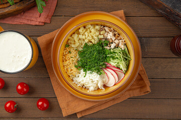 Cold summer russian soup okroshka with kefir on wooden decorated background