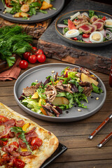 Meat salad with greens plum and pine nuts on gray plate