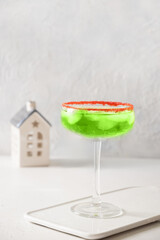 Xmas Green Punch in glass decorated red sugar rim on white table. Cocktail make of cool lime sherbet. Tasty drink for Christmas holiday.