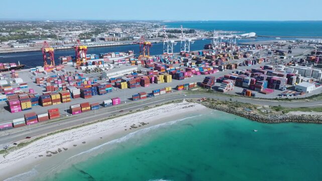 Aerial view of the vibrant Fremantle port container terminal meeting the turquoise ocean, a stark contrast to the industrial landscape, Fremantle, Western Australia, Australia.