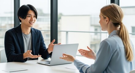 Obraz premium Two professionals collaborating on a project at a modern office space, Man and woman discussing business strategy during meeting in contemporary office environment