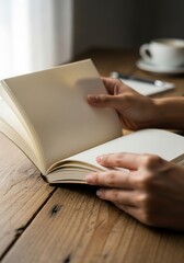 Naklejka premium Hands turning pages of a blank notebook on a wooden desk in a serene workspace