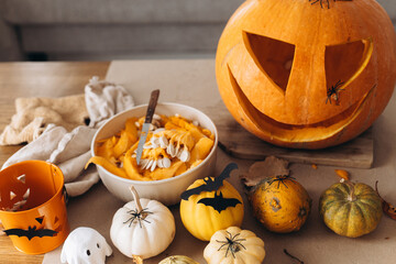 Making jack o lantern. Carving halloween pumpkin on table with spooky halloween decor, trick or...