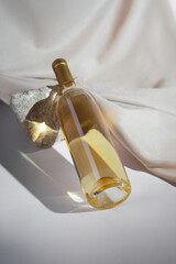 White Wine bottle mockup featuring golden liquid, elegantly positioned on textured stone, with soft fabric backdrop, ideal for branding and design purposes with copy space