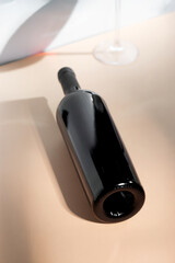 Red wine bottle mockup positioned on a smooth surface with elegant glassware in the background, ideal for branding and design projects showcasing beverage concepts