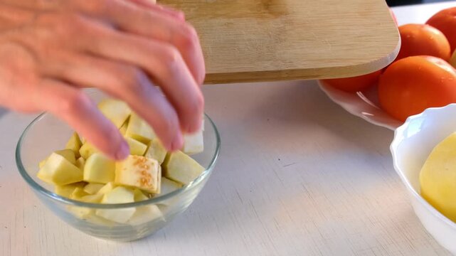 Chef woman hands cooking putting chopped eggplant on diced pieces into glass bowl. Culinary skills techniques, homemade prepare healthy meal, cook domestic food vegetable, cuisine, fresh ingredient.