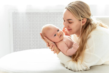 a mom with a baby, a mother holding a small newborn baby in her arms, kissing and gently hugging, happy motherhood, a family with a small child