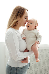 a mom with a baby, a mother holding a small newborn baby in her arms, kissing and gently hugging, happy motherhood, a family with a small child