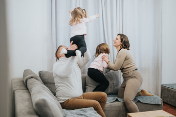 Obraz premium A joyful moment where parents and children share playful interactions in a comfortable home environment, fostering love and bonding.