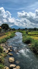 River flows, sky with clouds, greenery, mountain in background