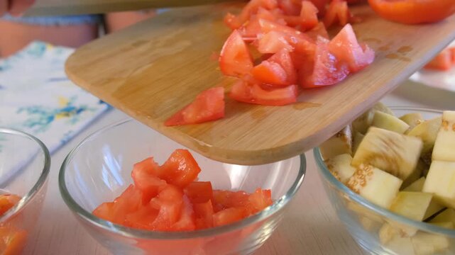Chef woman hands putting chopped tomatoes from cutting board into glass bowl cooking on kitchen. Culinary skills techniques, homemade prepare healthy meal, cook domestic food vegetable, cuisine.