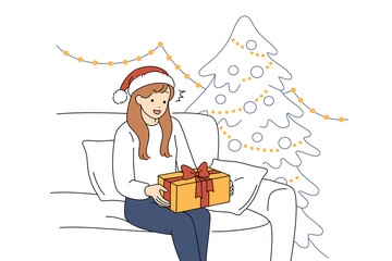 A Cheerful Woman with a Wrapped Christmas Gift by a Decorated Tree in Her Cozy Home