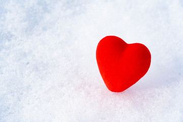 A small red heart lying on pristine white snow, symbolizing simplicity, love, and the purity of...