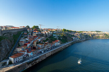 Obraz premium Scenic view of colorful hillside houses and riverside promenade along the Douro River in Vila Nova de Gaia, Porto, Portugal.
