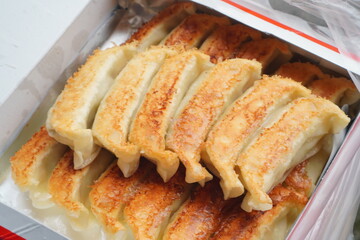 香ばしく焼き上がった宇都宮餃子のアップ写真　黄金色の焼き目が美味しそうに並ぶテイクアウト餃子　中華料理の定番メニューで家庭料理や外食、食欲をそそる食文化を表現したフードイメージ