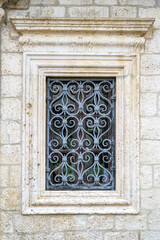 Beautiful ornate window graces a stone building in Kotor, showcasing stunning craftsmanship.