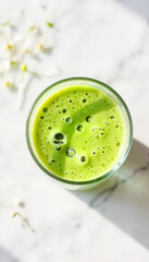 Green smoothie in glass on marble surface with fresh ingredients  