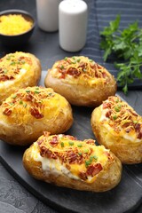 Tasty stuffed baked potatoes on black table, closeup