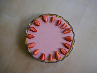 Overhead view of strawberry tart with fresh strawberries on wooden table