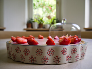 Homemade strawberry tart with fresh strawberries in a vintage ceramic dish on rustic wooden table