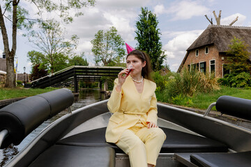 A girl drinks a drink while sailing on a boat in the countryside celebrating a birthday.