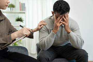 man cover face felling sad from health problems. psychiatrist is recording the patient's condition...