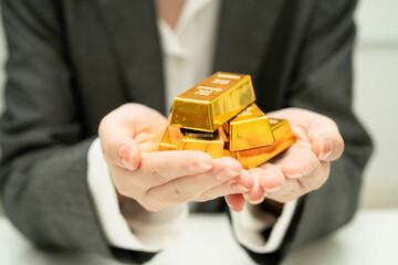 Asian woman holding gold bar in finance business.