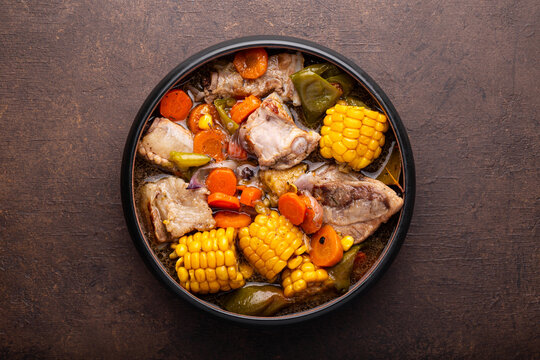 Chilean cuisine of Latin America. Traditional Chilean cazuela de cerdo. Pork soup with potatoes and corn, stew with corn and carrots on dark background top view