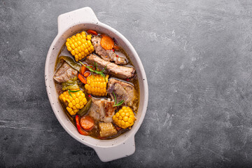 Chilean cuisine of Latin America. Traditional Chilean cazuela de cerdo. Pork soup with potatoes and corn, stew with corn and carrots on grey background top view copy space for text