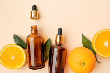 Cosmetics mockup for branding. Brown glass cosmetic containers with dropper, fresh oranges on beige background flat lay. Natural cosmetics concept with vitamin C, organic aroma oil, citrus extract