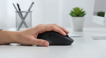 A hand uses a computer mouse on a table, a fundamental tool for digital work environments.Concept of office technology and productivity.