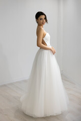 Fototapeta premium Beautiful bride in modern A-line gown with open back, elegant and stylish indoor portrait