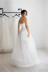 Bride in a strapless white gown turns back with elegance, showcasing the dress in soft lighting.