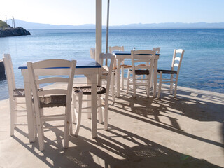 Kitries village, Mani Peninsula - Greece - September 21 2025 - Greek seaside taverna. View of the terrace with shadows cast by the late afternoon sun. Tables and chairs.