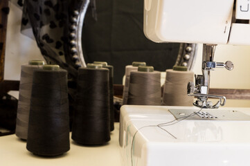 Sewing machine with spools of gray thread and a mirror in the background